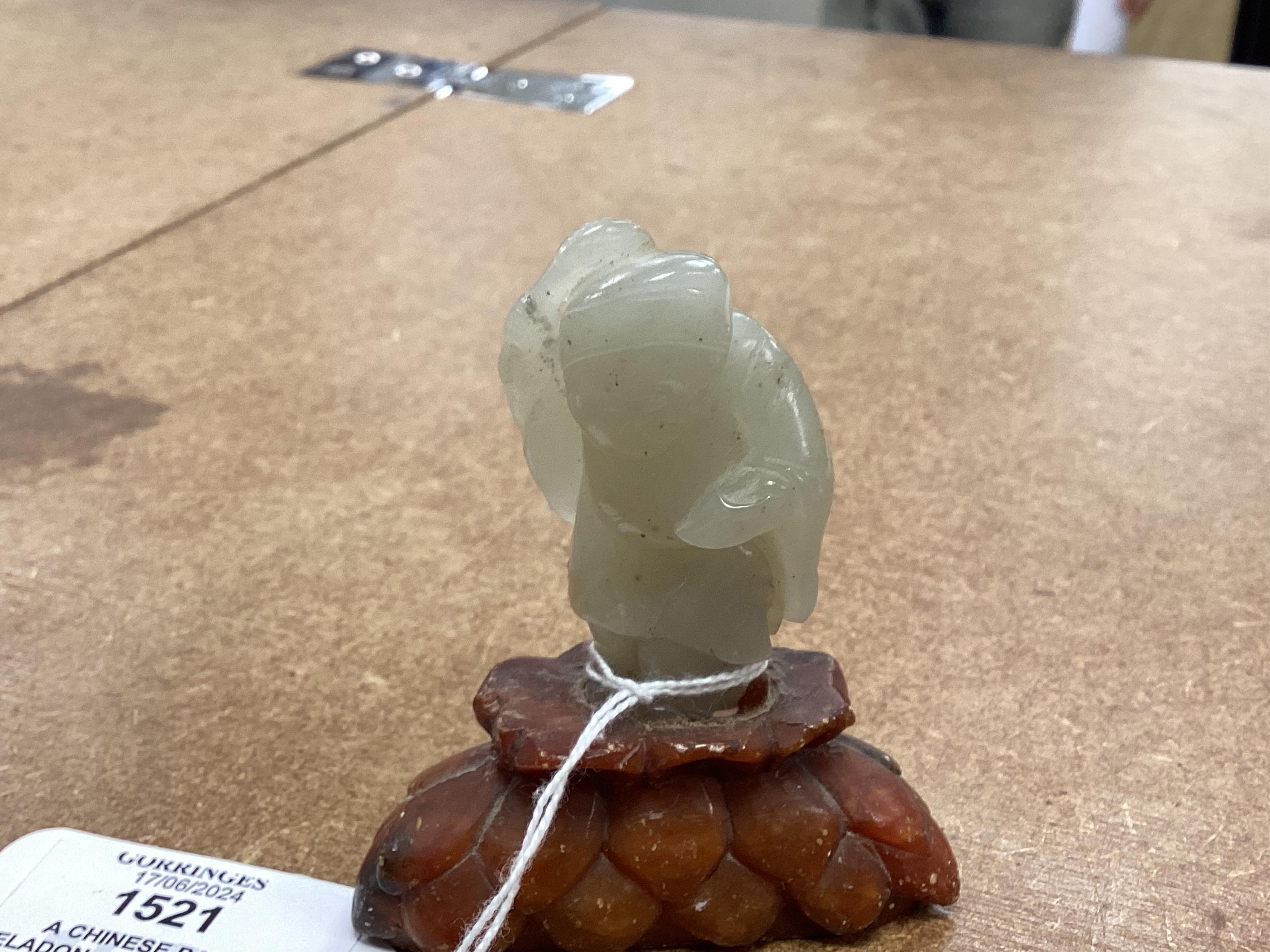 A Chinese pale celadon jade figure of a man holding a fly whisk, Qing dynasty, 5.2cm high, soapstone stand, total height 8cm high